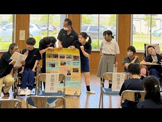 新聞委員会です。新聞をいつ発行するのかや、内容について質問がでました。最新号の新聞をもって、「みなさん、面白いことものっているので、読んでみてください。」と呼びかけていました。